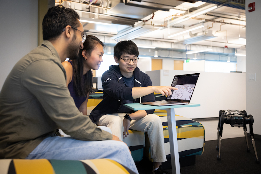 Students looking at computer with robot next to them