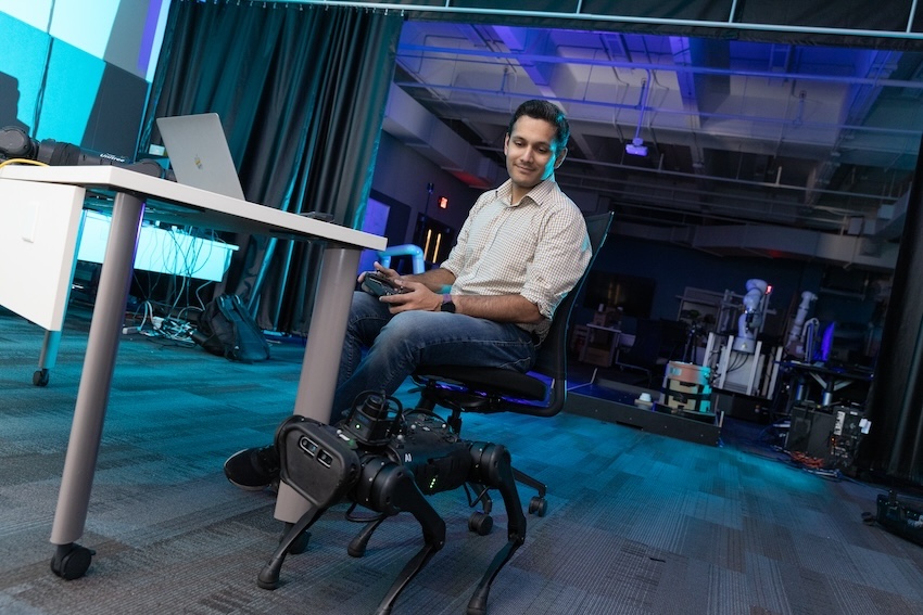 A man sitting in a chair with a dog robot in front of him