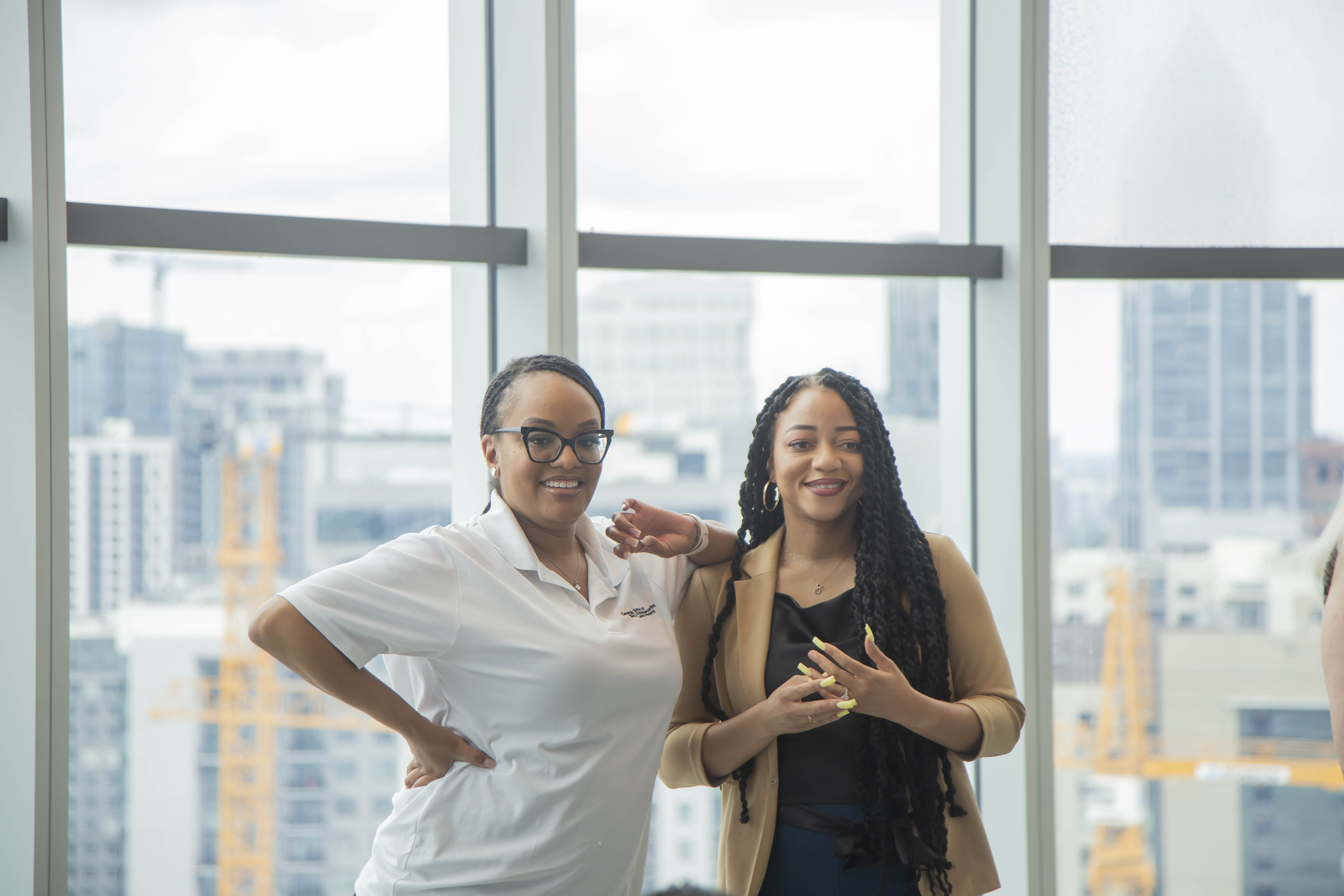 two women standing next to each other in front of a large window