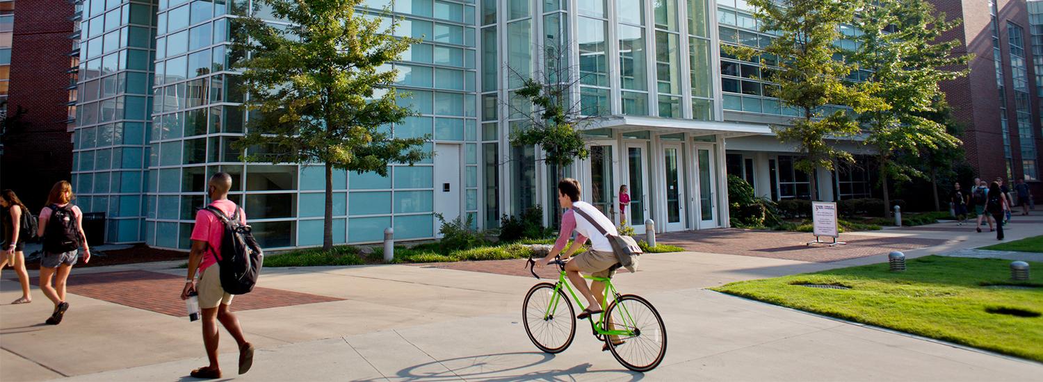 people walking and riding bikes outside of school building