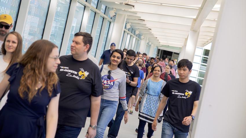 candid photo of new OMSCS alums and family members crossing binary bridge as part of campus walking tour in 2019 for spring graduation