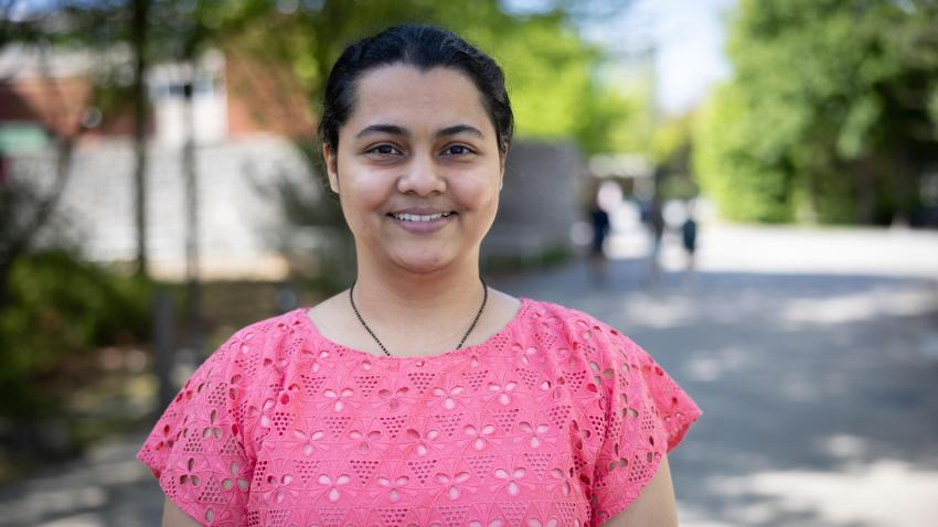 Woman in pink shirt, smiling outside 