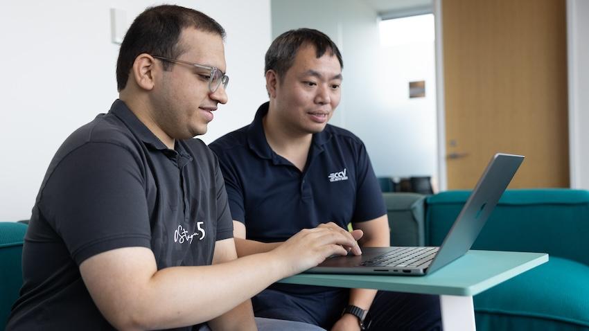 Two men look at a laptop screen