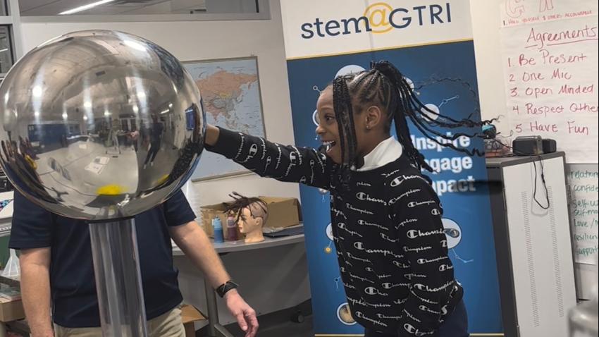 Little girl touching an orb that produces an electrical currant and causes her hair to stand up