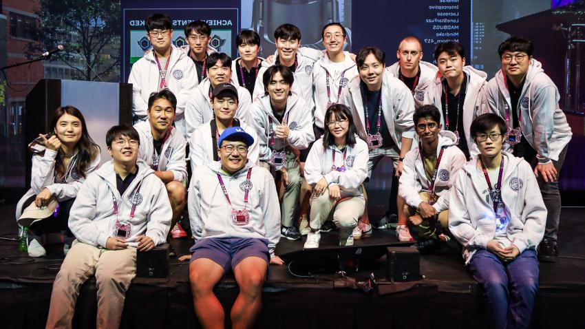 A group photo of Team Atlanta taken in a dark room. The team are all wearing matching grey hoodies.