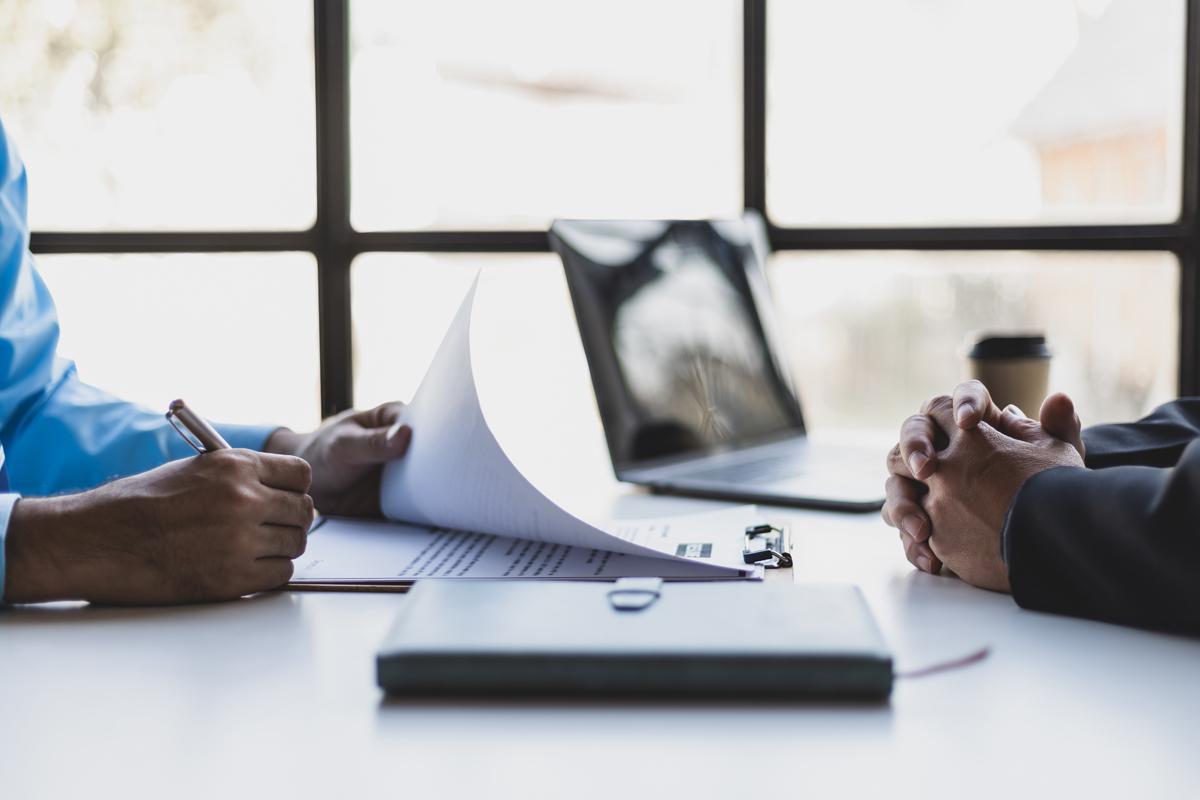 Two pairs of hands on a desk with a resume.