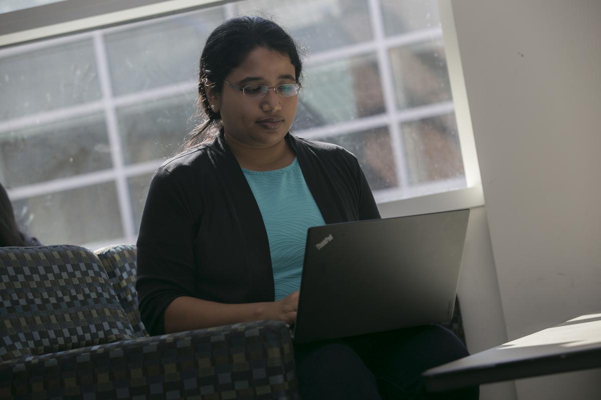 Woman working on laptop in a campus building